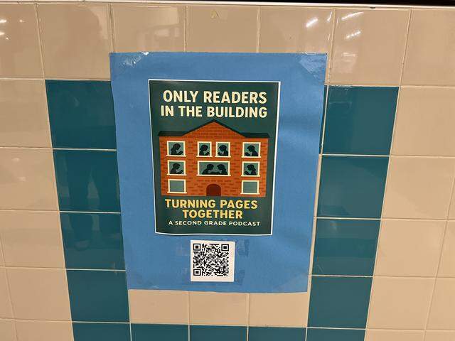 A poster advertising the podcast, “Only Readers in the Building – Turning Pages Together,” is seen in the hallway of Heritage Elementary School in Grapevine-Colleyville ISD on Thursday, March 12, 2026. Second-grade students discuss books they’re reading on the podcast twice a week.